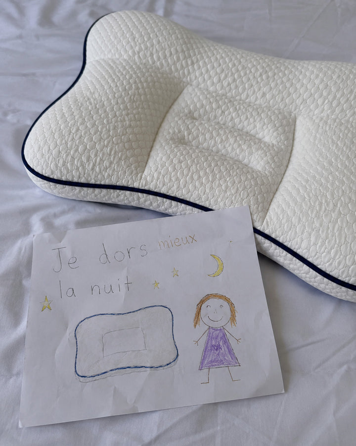 Photo naturelle d’un dessin d’enfant posé à côté de l’oreiller ergonomique sur un lit.
